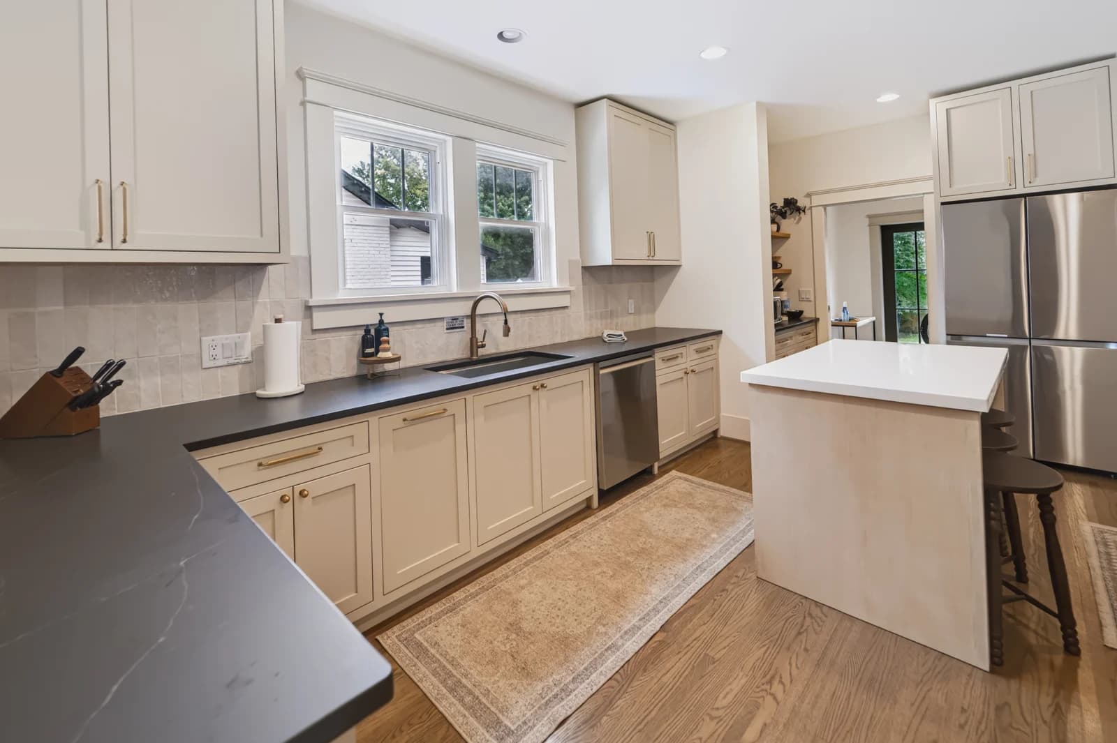 Kitchen with pale cabinets, brass handles, dark countertops and a central island