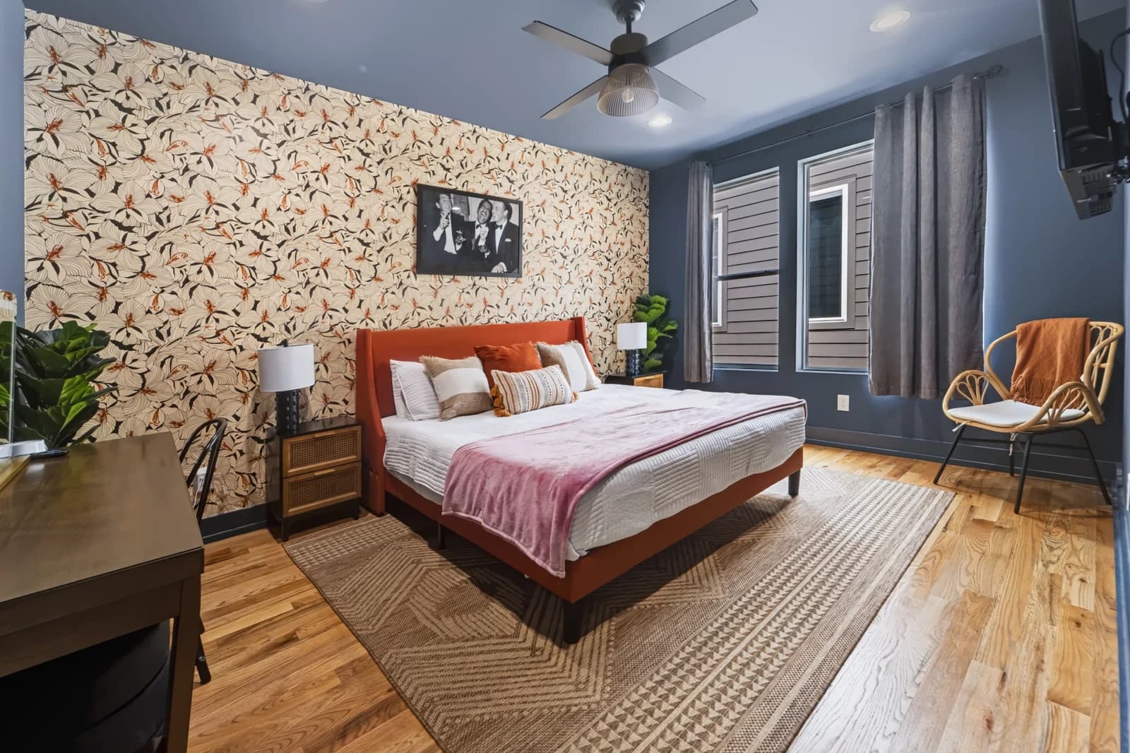 Bedroom with blue walls, patterned wallpaper, an orange headboard and a pink throw