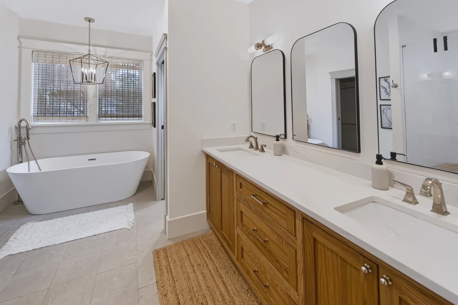 Bathroom with a double wood vanity, black-framed mirrors and a freestanding bathtub